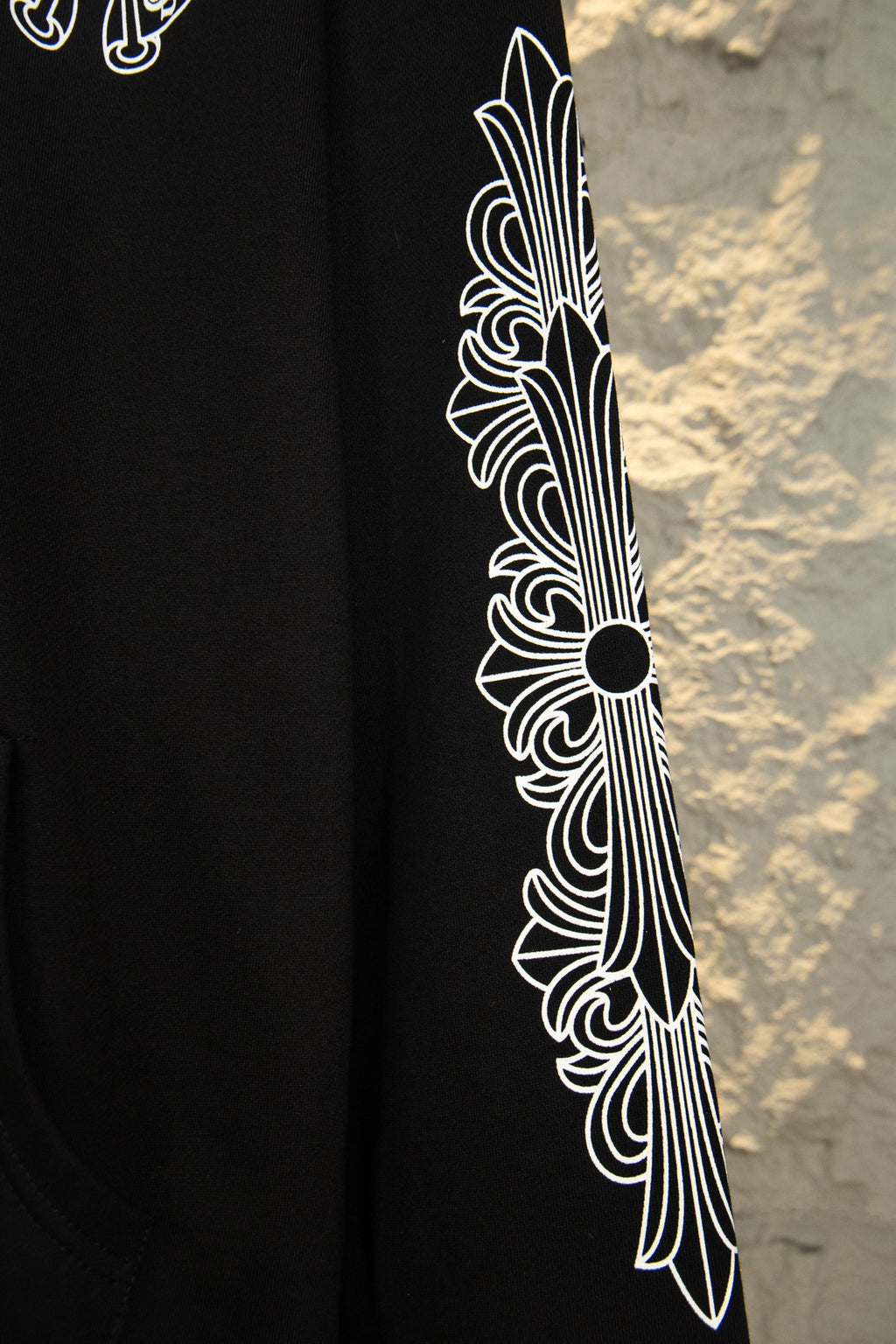 Black hoodie sleeve close-up with white feather-style graphic