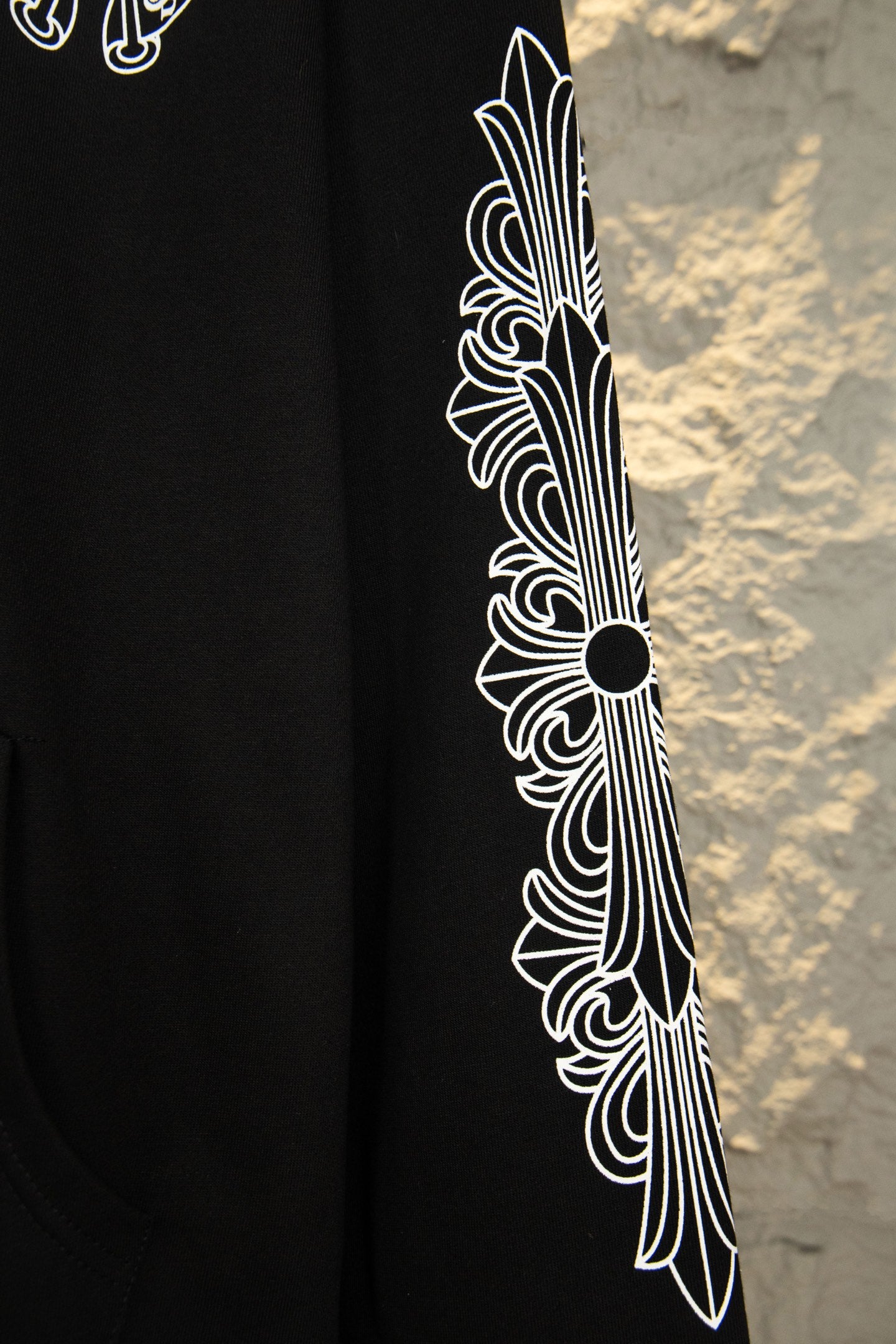 Black hoodie sleeve close-up with white feather-style graphic
