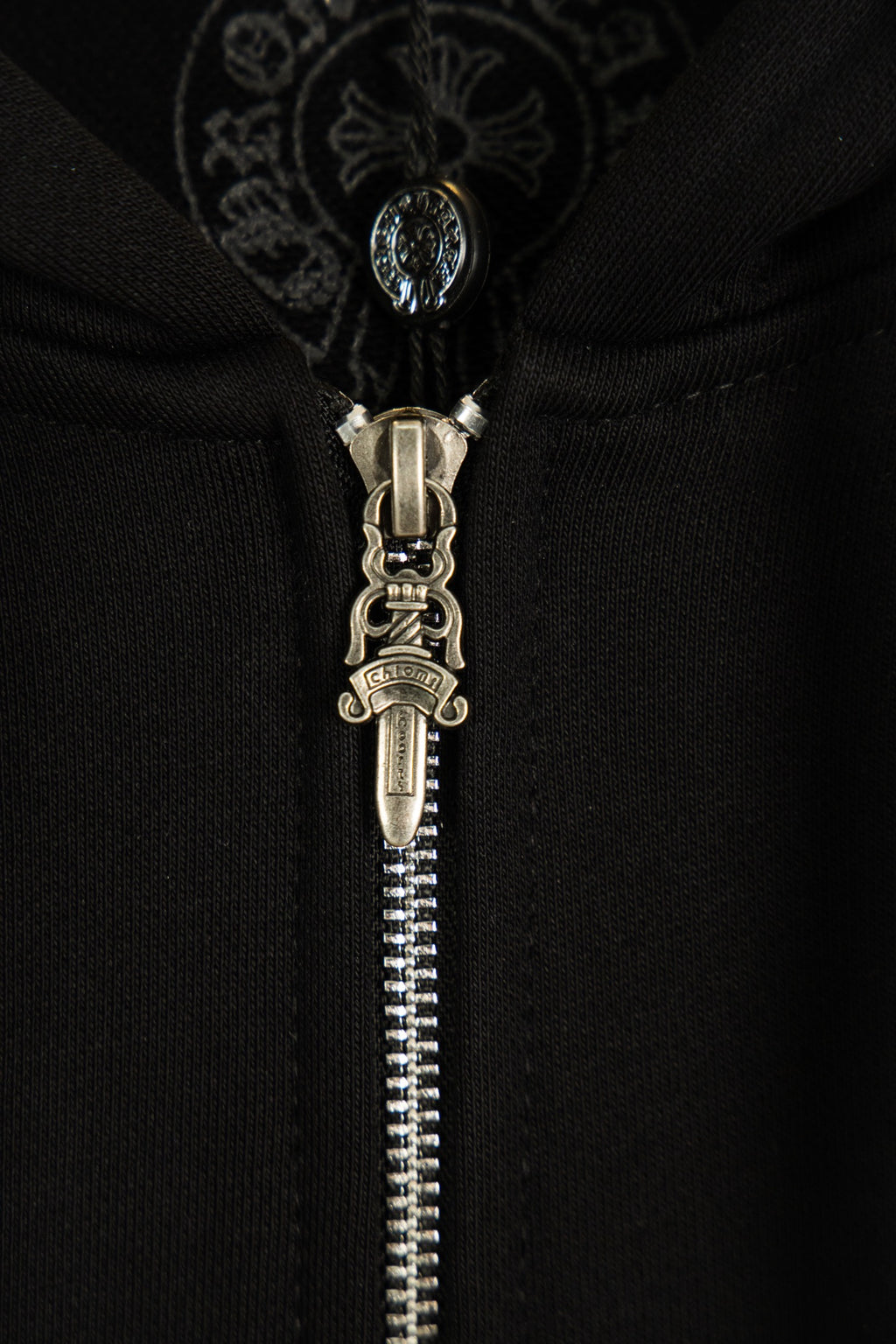 Black hoodie with detailed metal zipper and ornate hood drawstring pull.