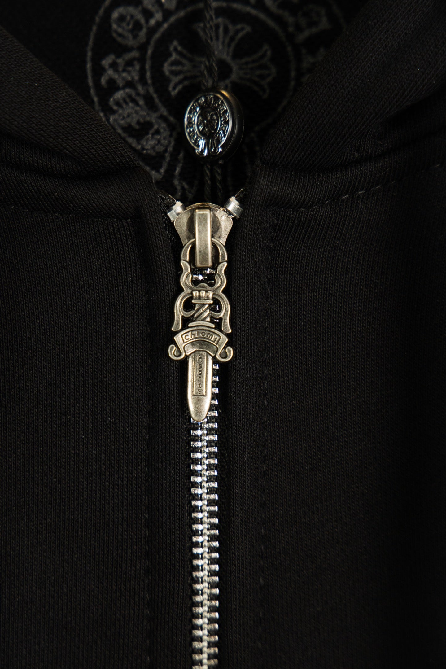 Black hoodie with detailed metal zipper and ornate hood drawstring pull.