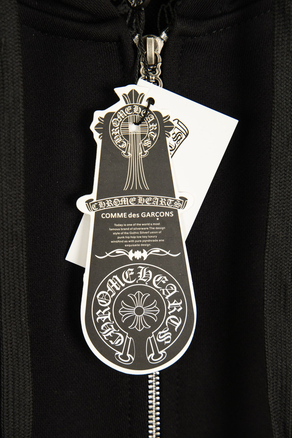Black hoodie with silver zipper pull and hanging brand shield tag.