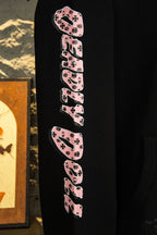 Black hoodie sleeve with pink-and-black repeating graphic text design.