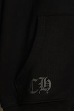 Black hoodie inner seam with stitched label; small signature graphic.