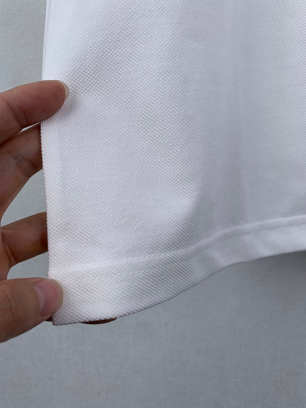 Gucci white T-shirt side seam close-up held by hand