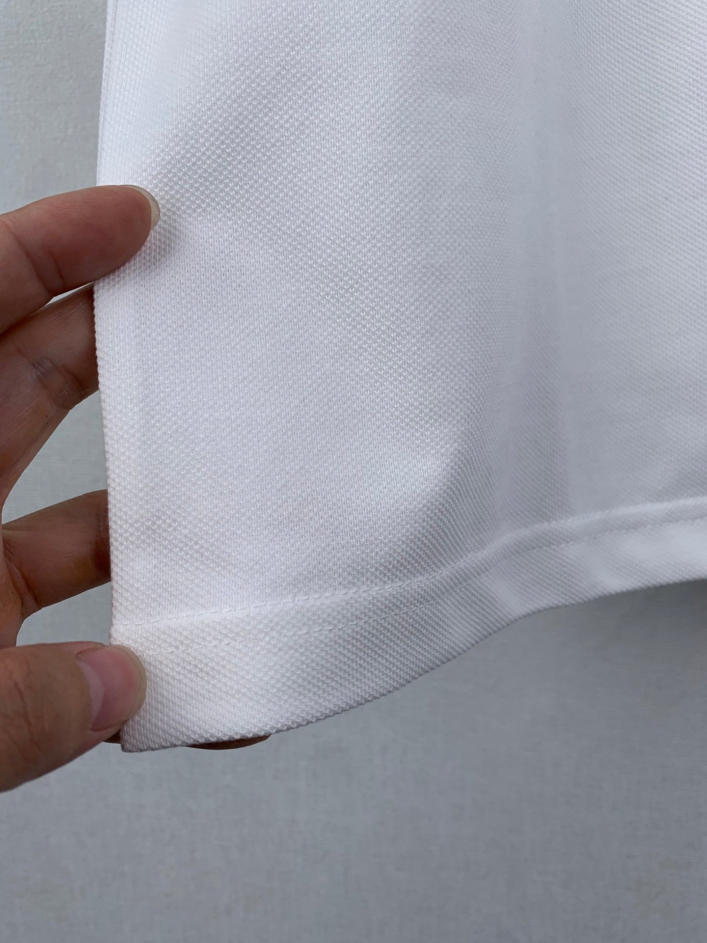 Gucci white T-shirt side seam close-up held by hand