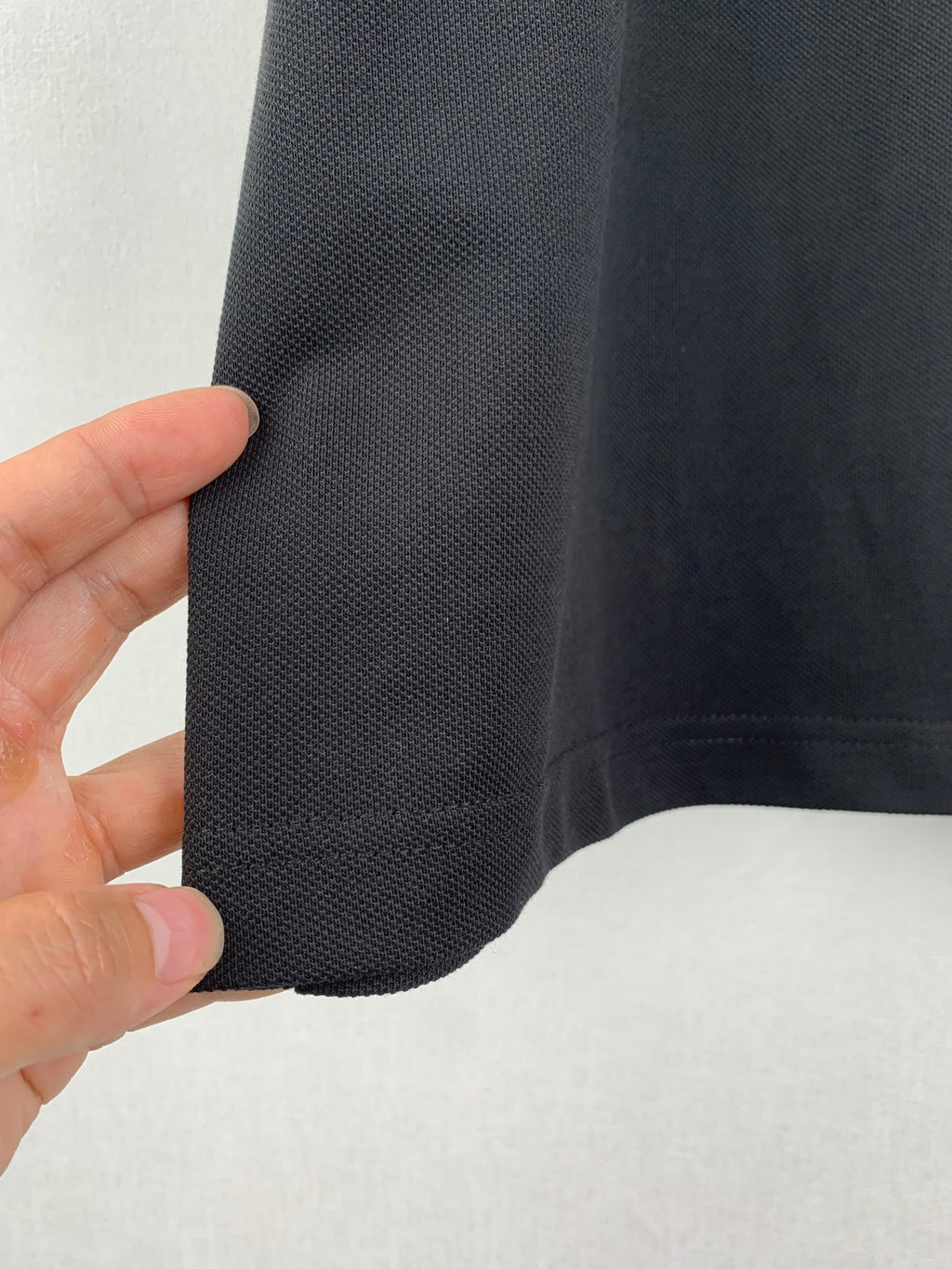 Side seam and sleeve edge close-up on a dark crew-neck T-shirt