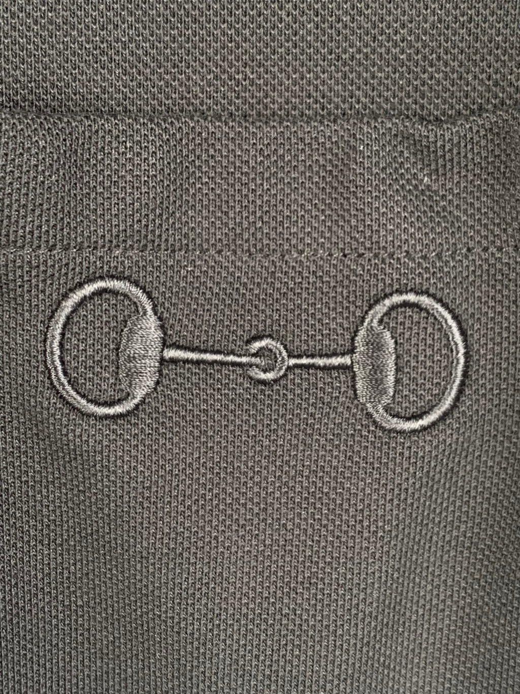 Close-up of Gucci label with metal-like emblem detail on a dark T-shirt