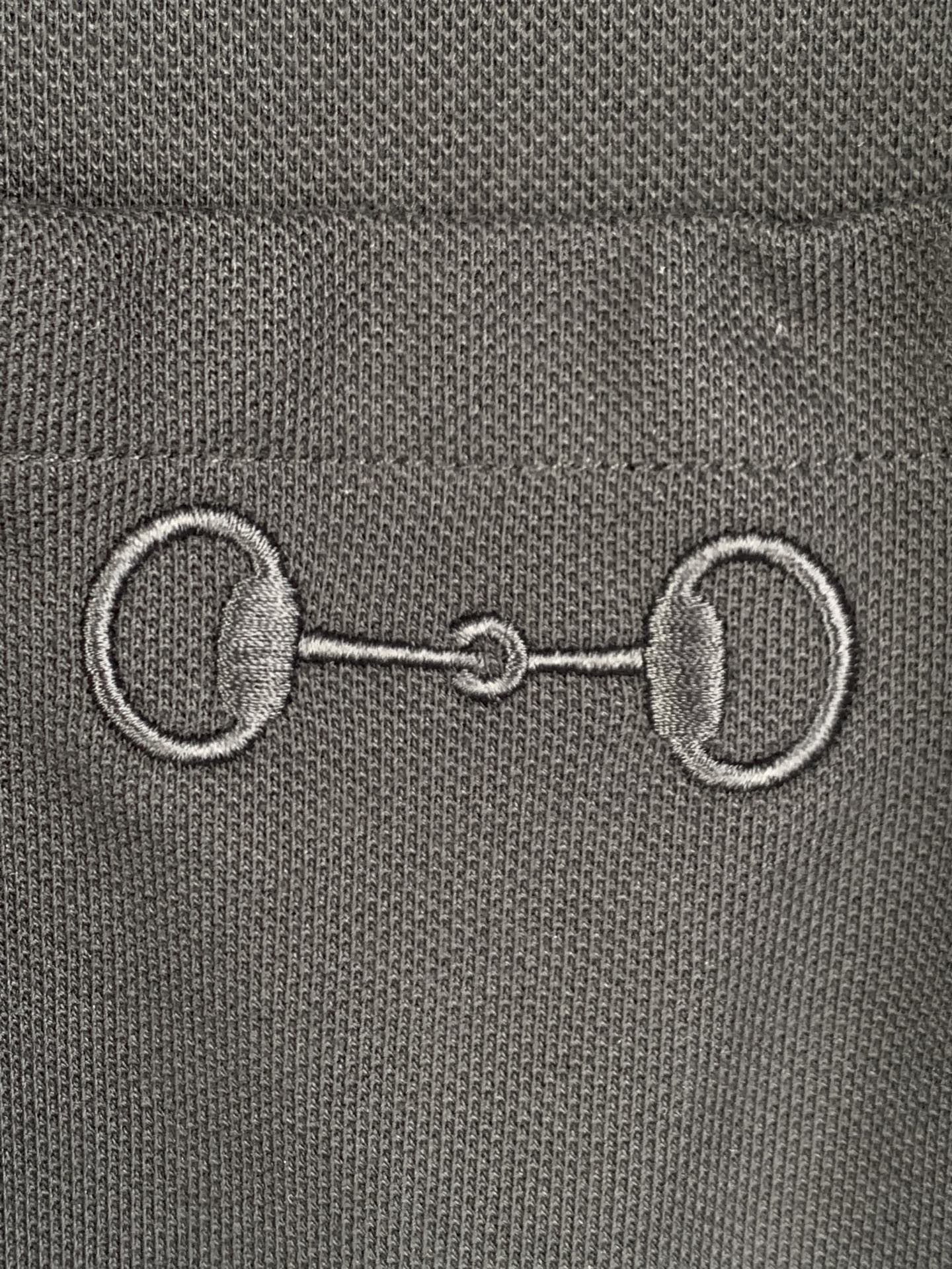 Close-up of Gucci label with metal-like emblem detail on a dark T-shirt