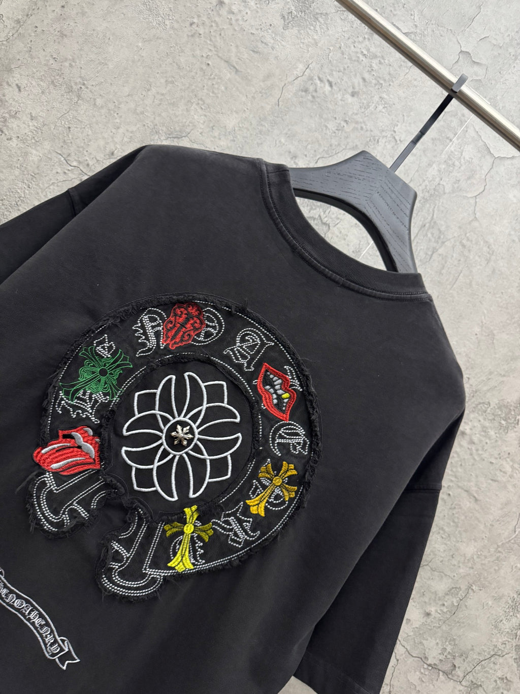 Black T-shirt close-up of circular flower and character patch embroidery.