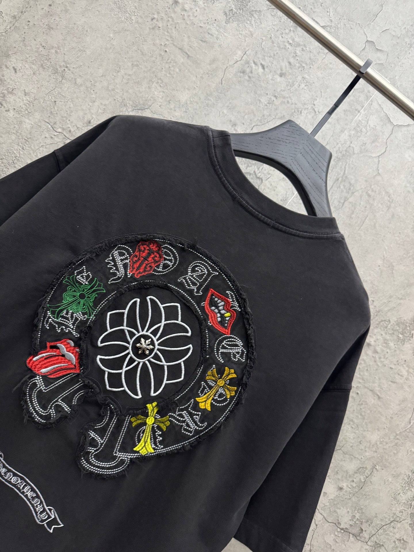 Black T-shirt close-up of circular flower and character patch embroidery.