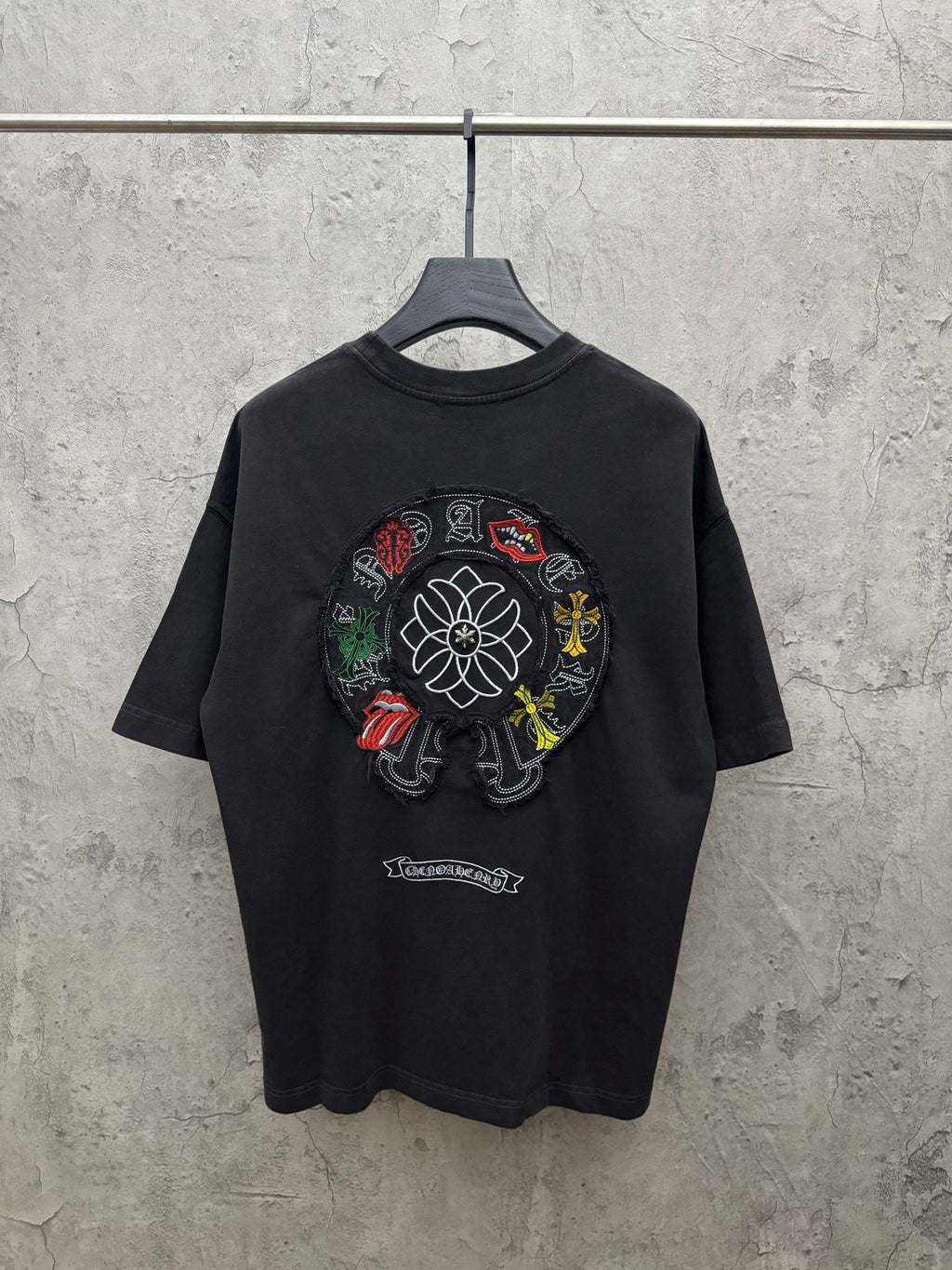 Black crewneck short-sleeve T-shirt with large circular flower embroidery on back.