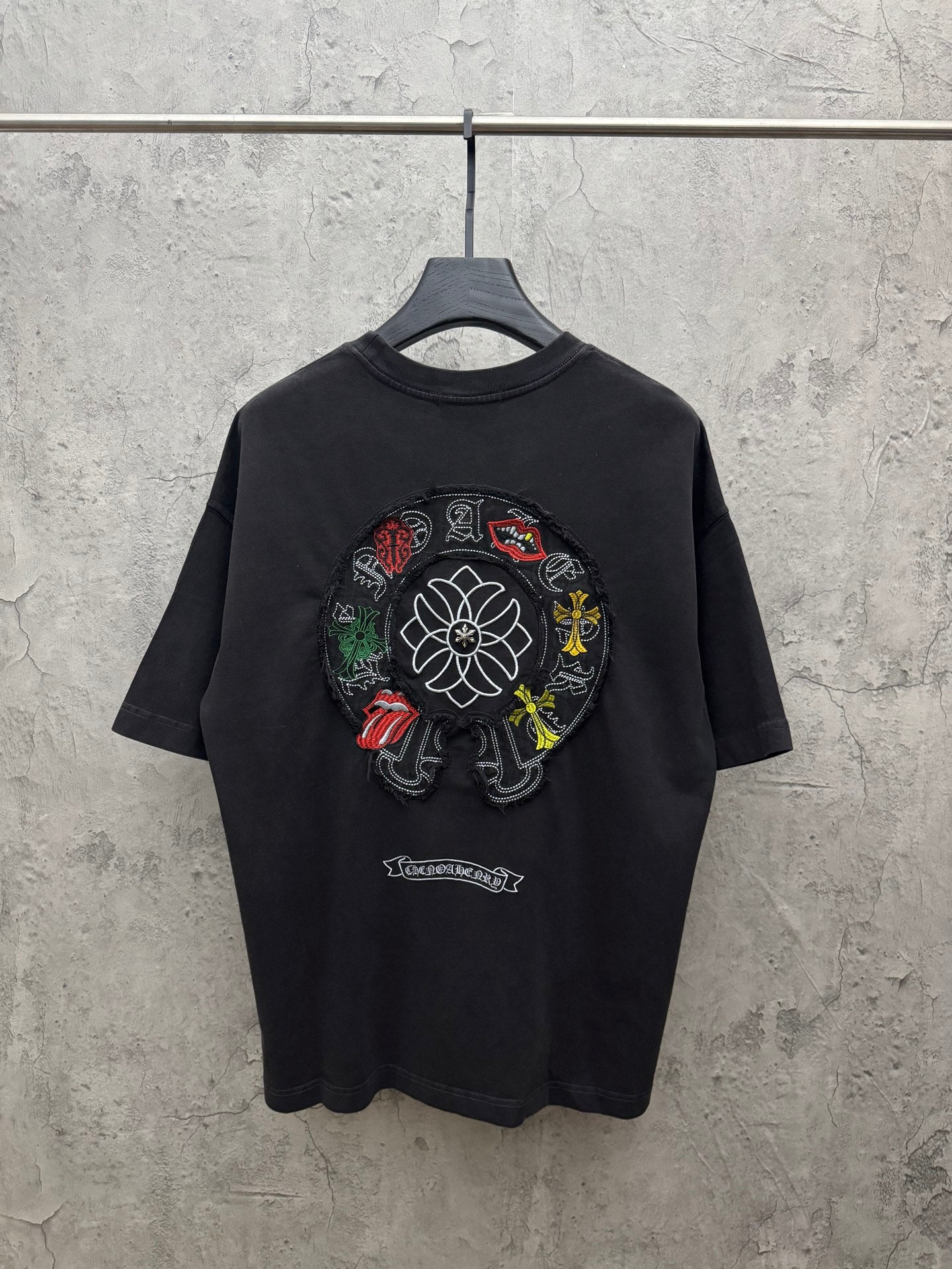 Black crewneck short-sleeve T-shirt with large circular flower embroidery on back.