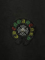 Black fabric close-up of white flower logo with multicolor stitched accents.