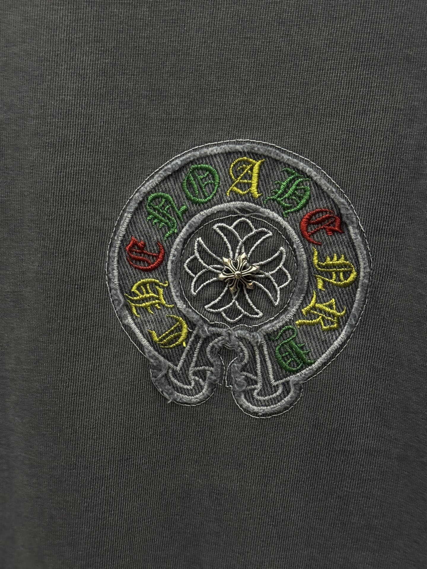 Grey T-shirt fabric with circular multicolor embroidered flower emblem