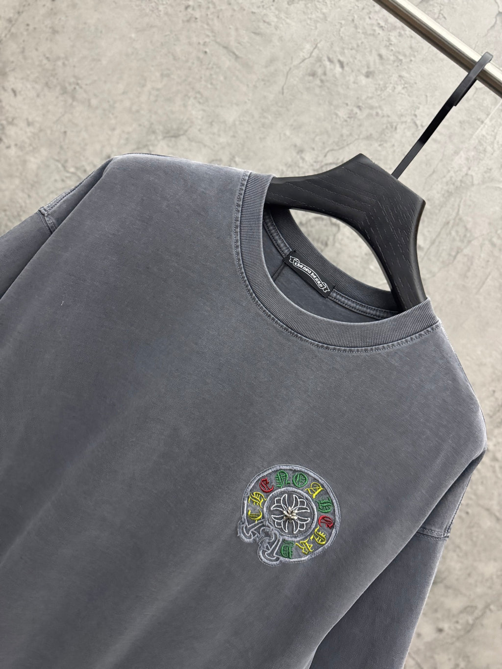 Grey T-shirt close-up with crew neck and small chest embroidered logo