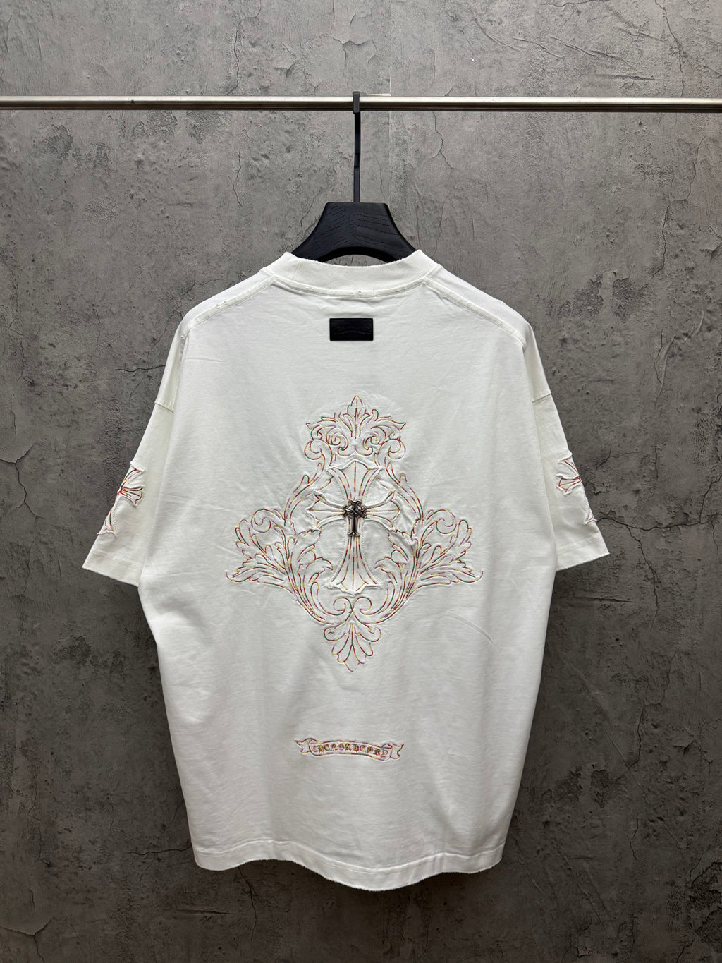 White short-sleeve T-shirt with large back cross embroidery and decorative script at hem