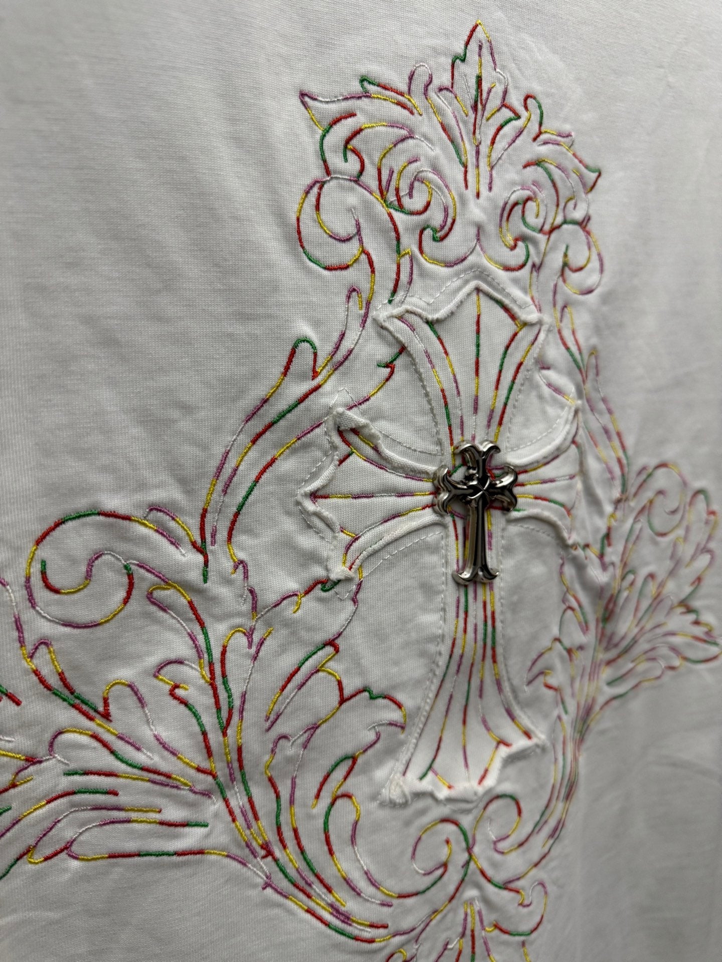 White short-sleeve T-shirt embroidery close-up of ornate cross with colorful thread accents