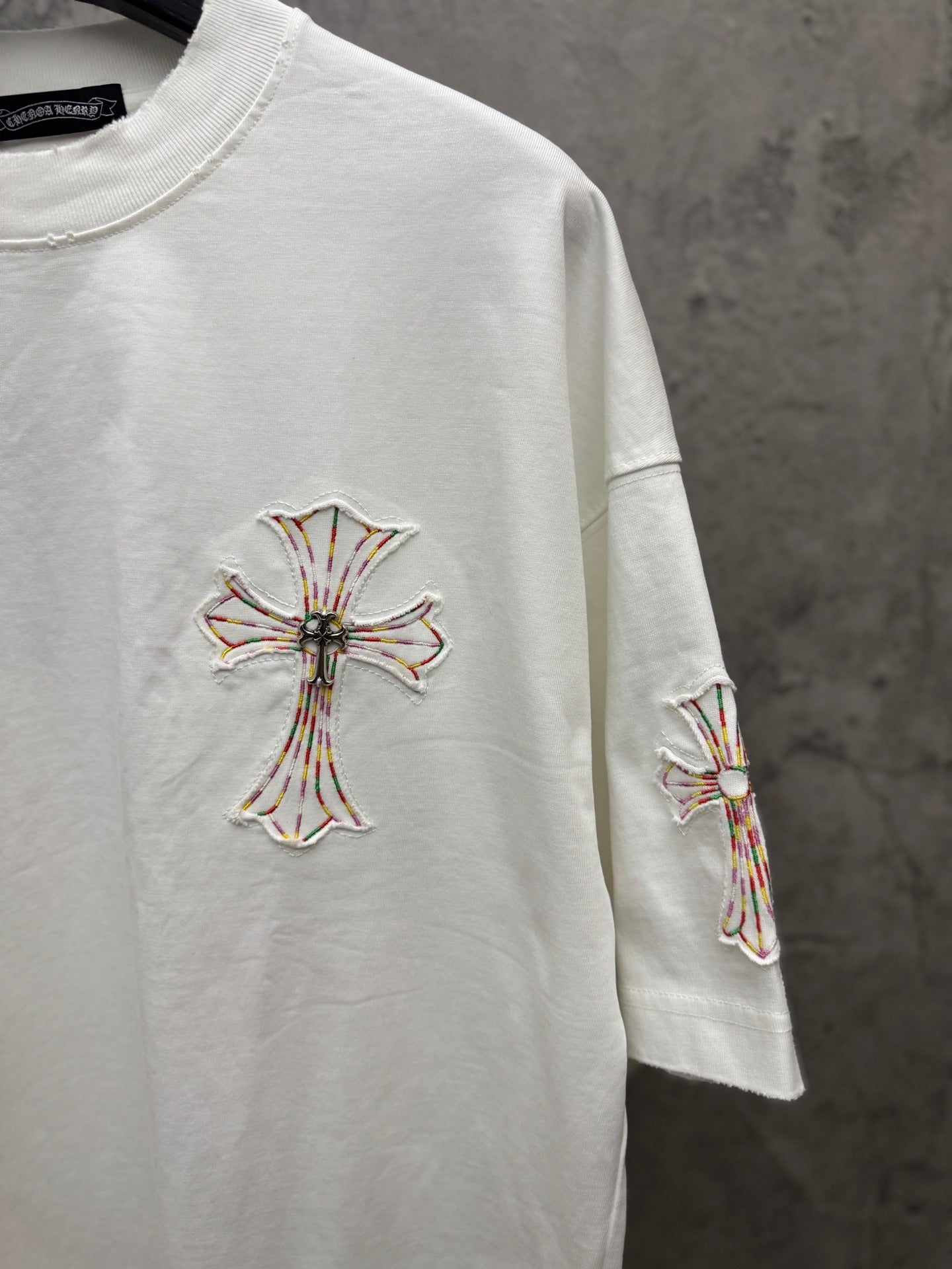 White short-sleeve T-shirt with cross embroidery on chest and matching sleeve motif