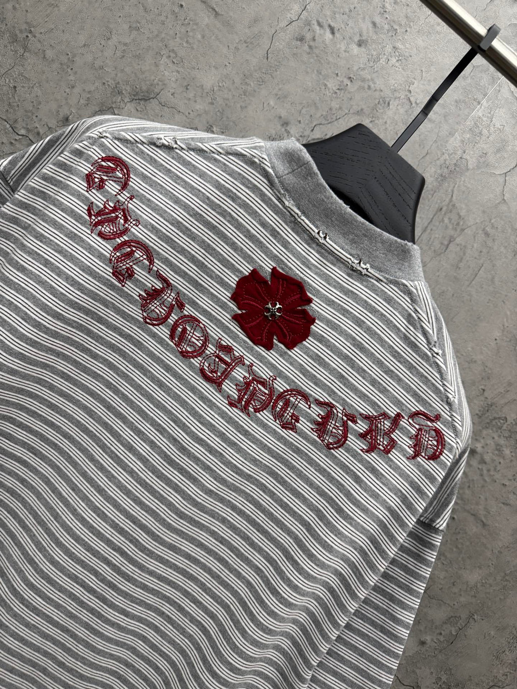 Striped short-sleeve T-shirt with red embroidered script and flower detail on upper back.