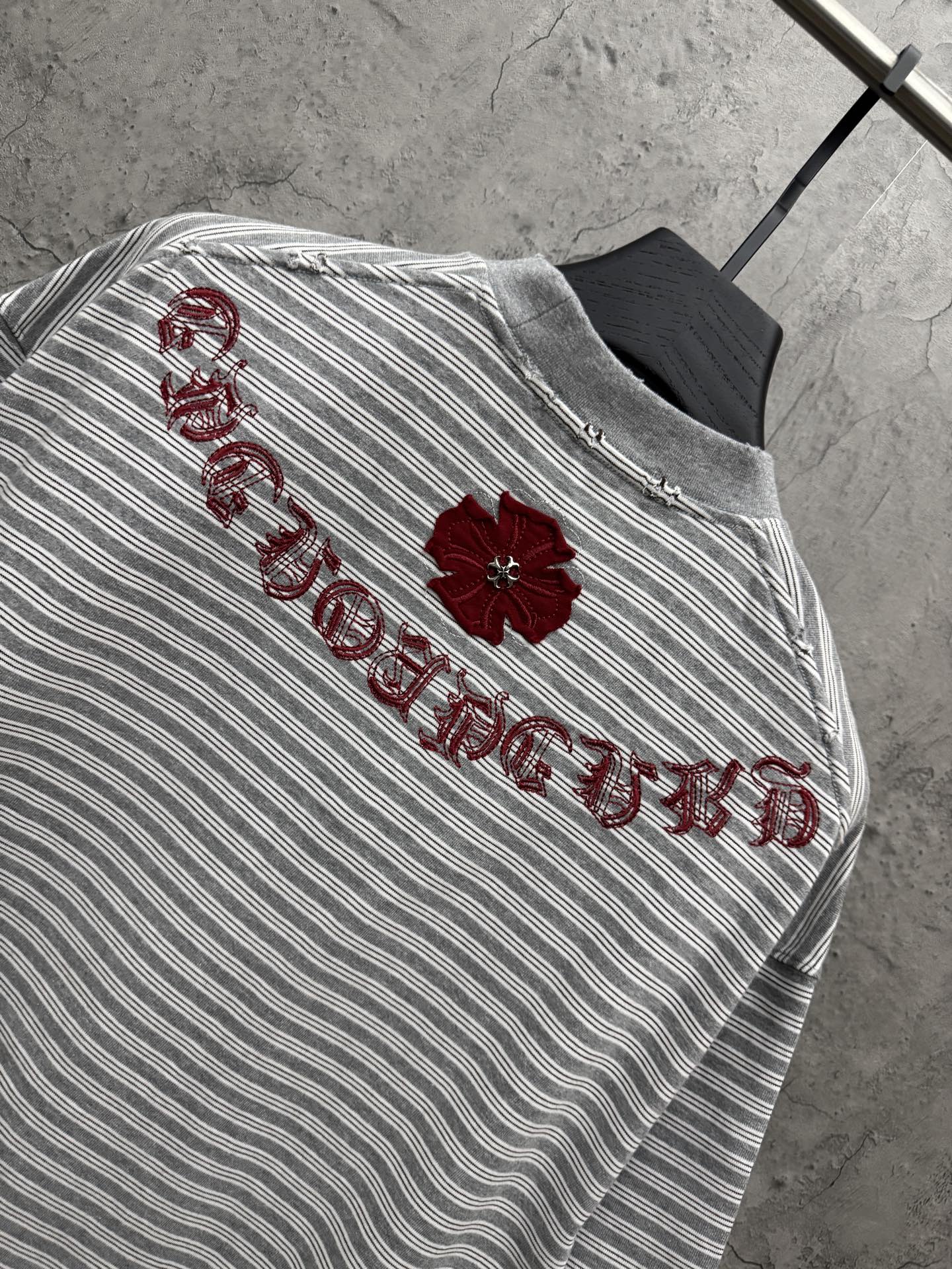 Striped short-sleeve T-shirt with red embroidered script and flower detail on upper back.