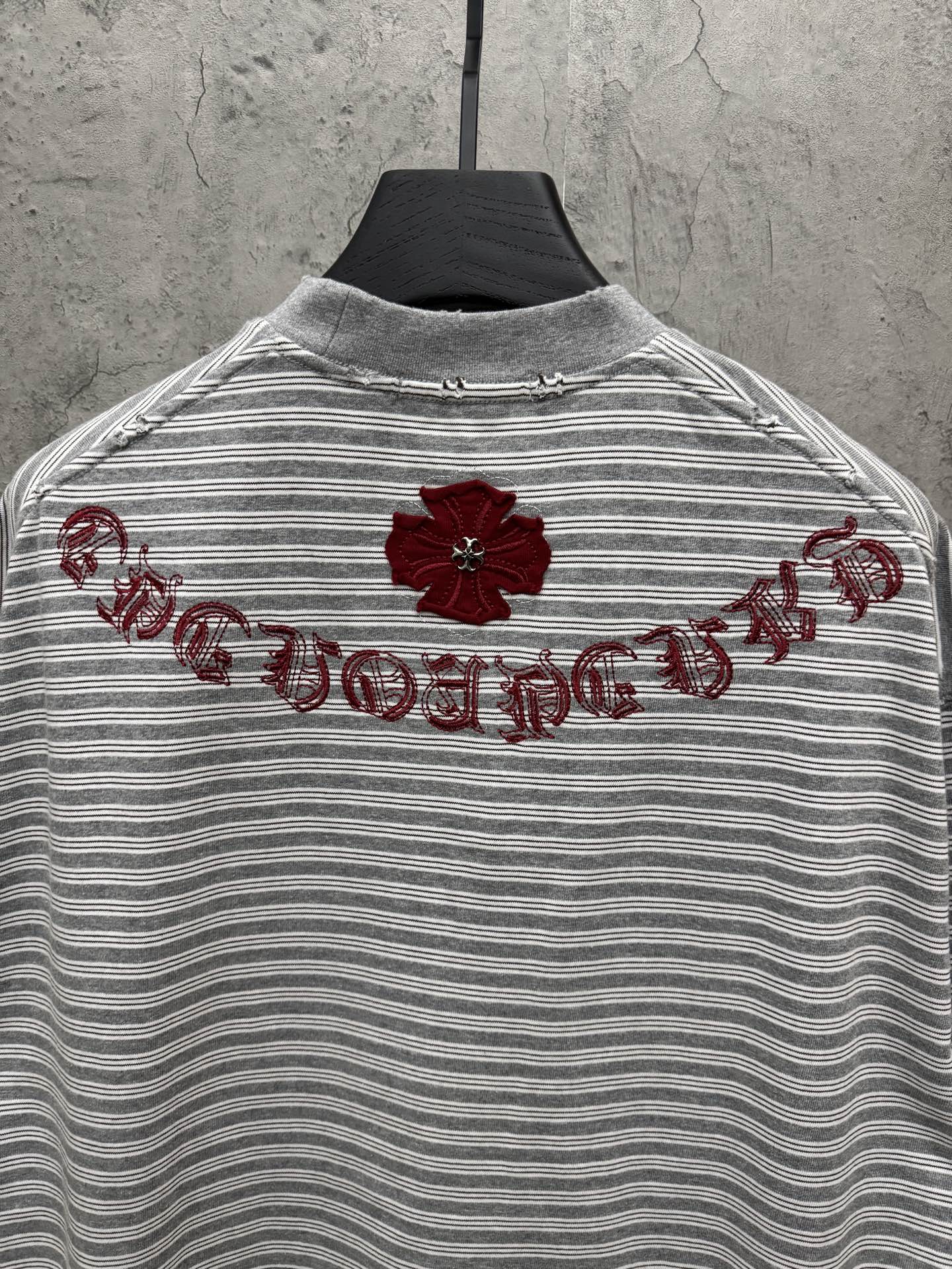 Striped short-sleeve T-shirt with red floral embroidery and script across upper back.