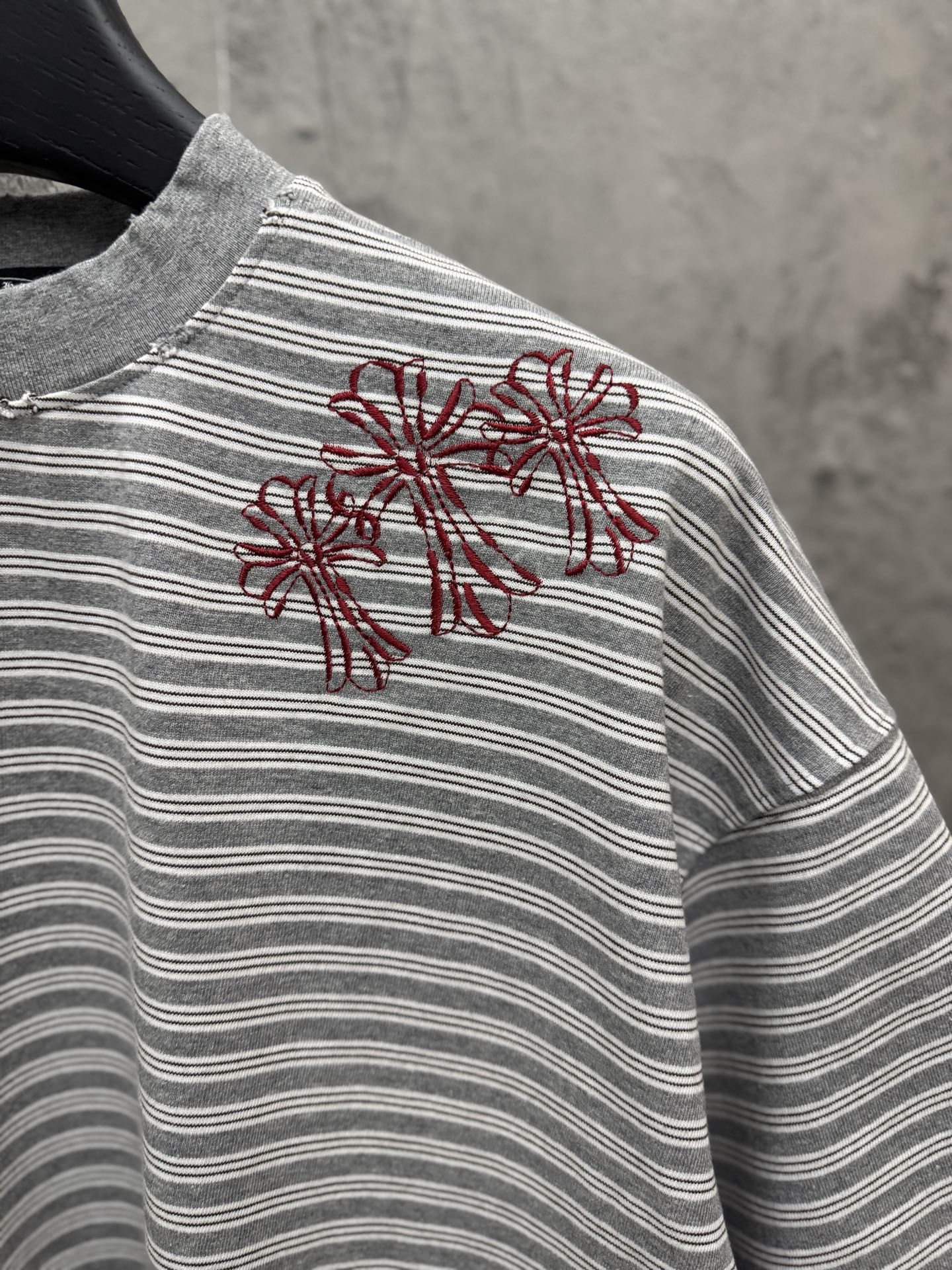 Striped short-sleeve T-shirt with red floral embroidery on left chest.