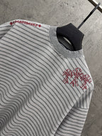 Close-up of striped short-sleeve T-shirt with red floral embroidery on sleeve front.