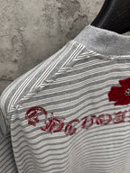 Striped short-sleeve T-shirt with red embroidered script along sleeve seam.