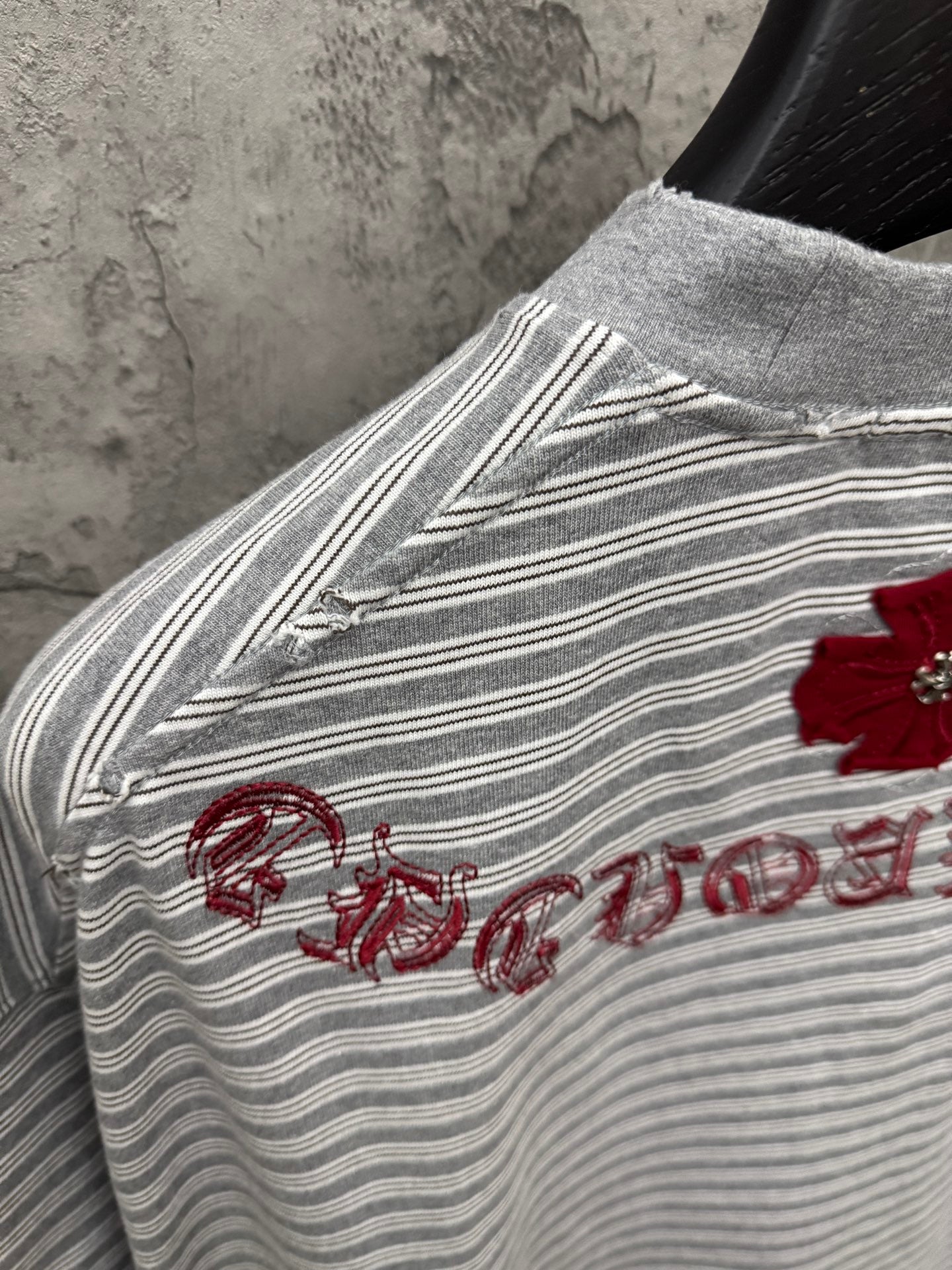Striped short-sleeve T-shirt with red embroidered script along sleeve seam.