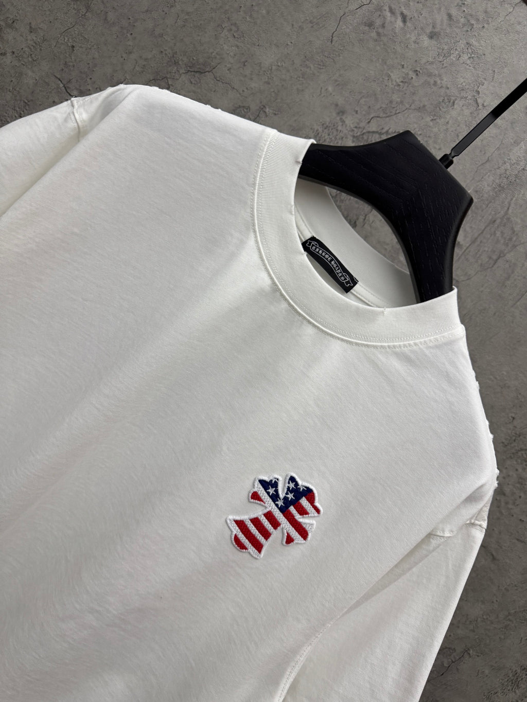 White T-shirt close-up: crew neck and small embroidered patriotic figure