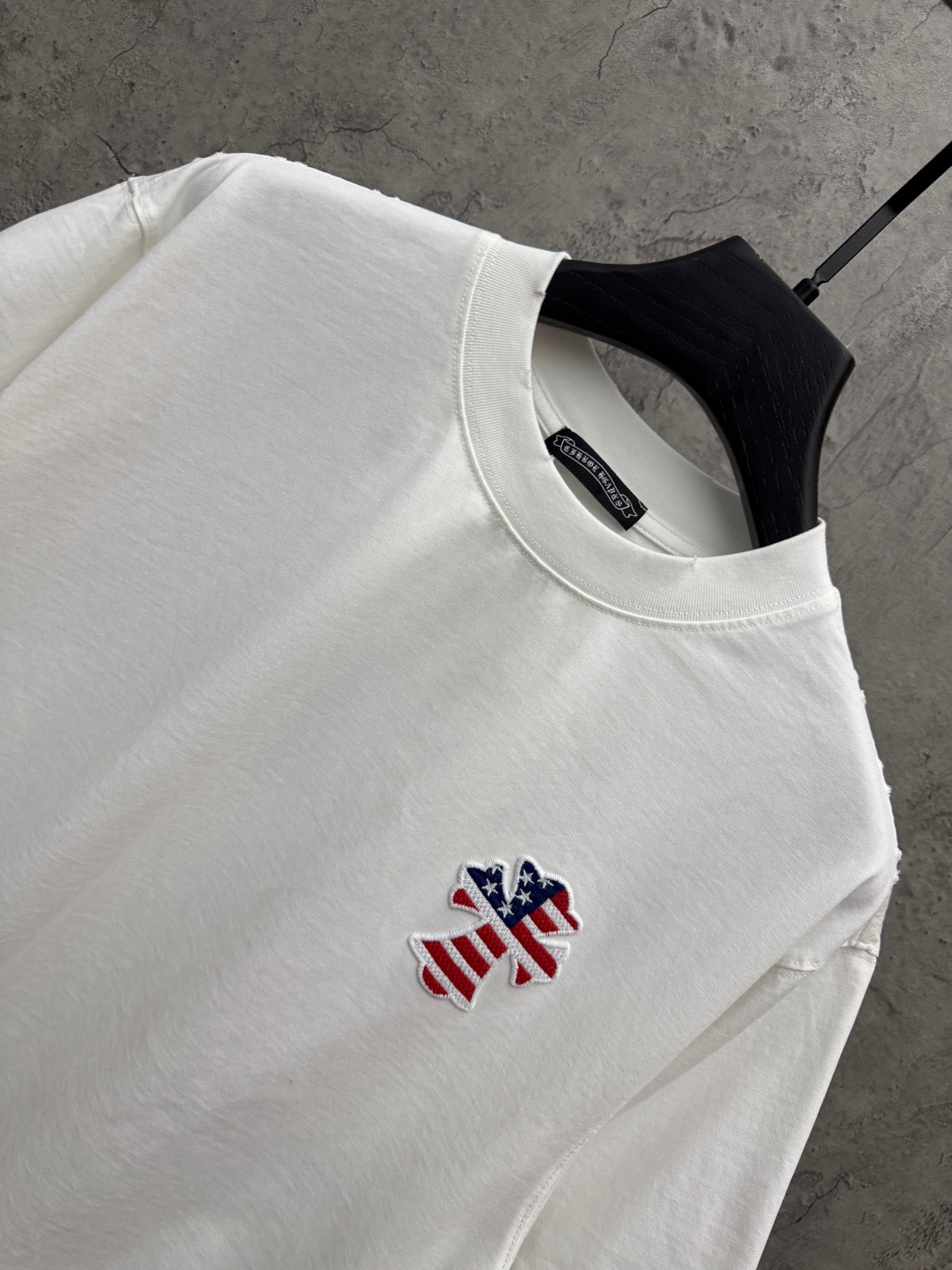White T-shirt close-up: crew neck and small embroidered patriotic figure