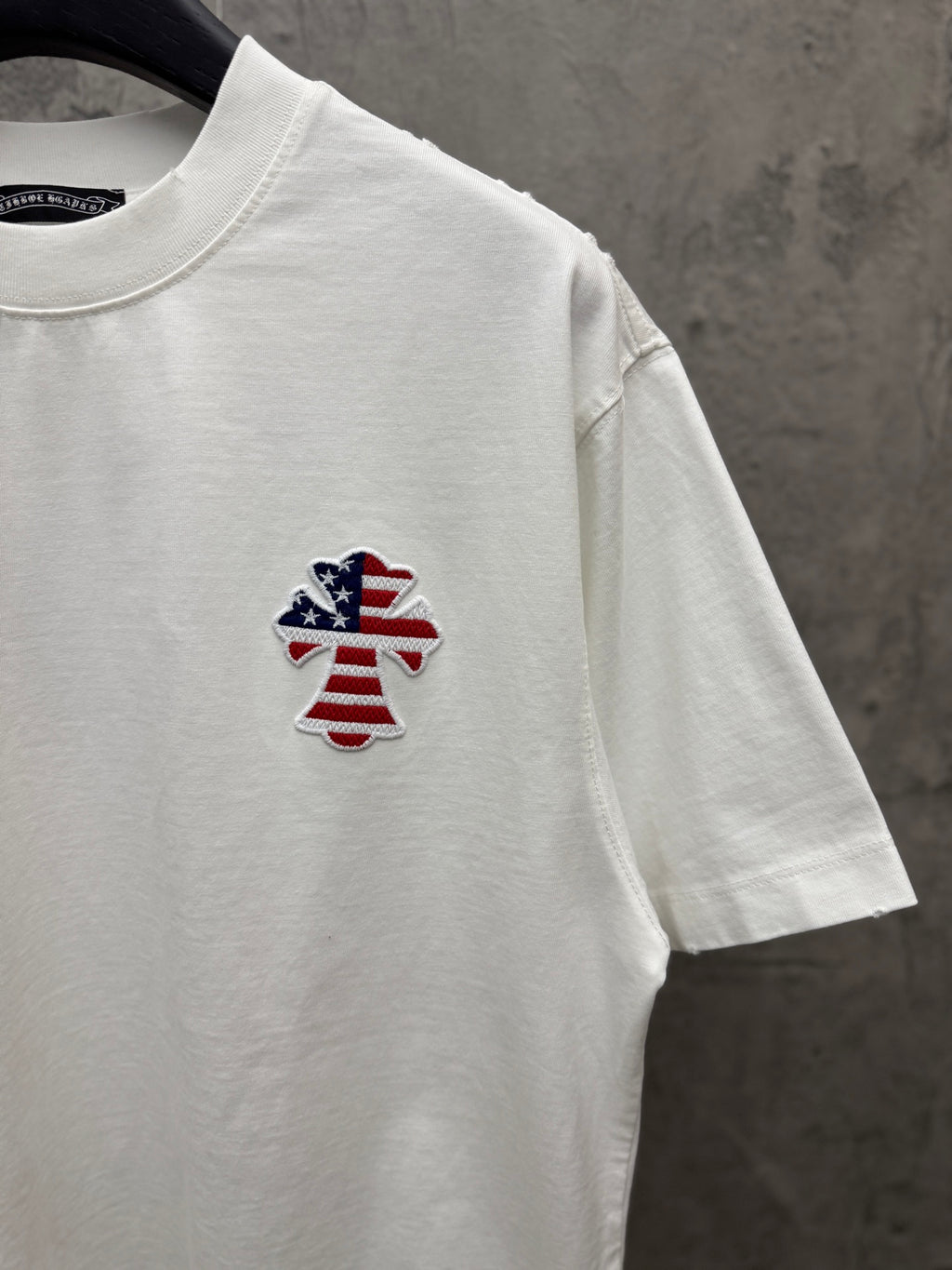 White short-sleeve T-shirt with small embroidered patriotic figure on chest