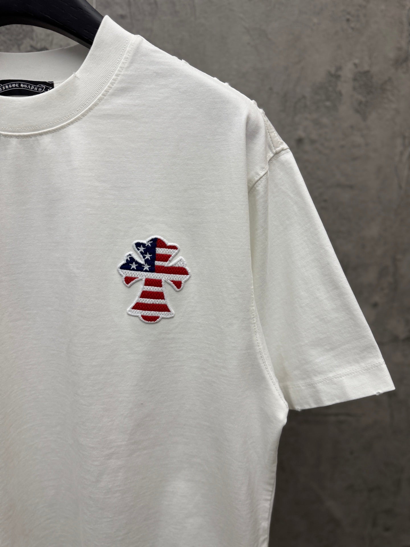 White short-sleeve T-shirt with small embroidered patriotic figure on chest