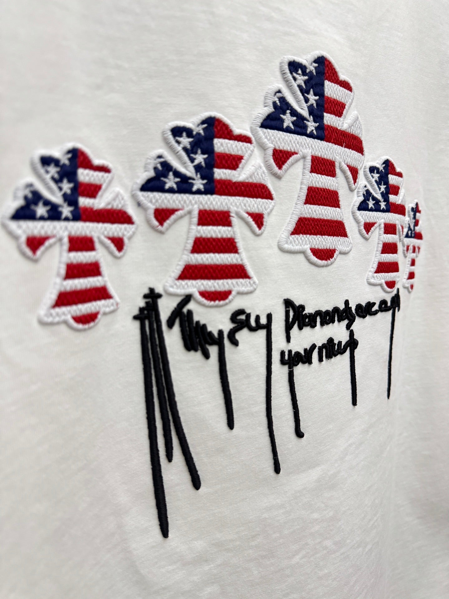 White T-shirt close-up: embroidered patriotic figures with drips and stars-and-stripes