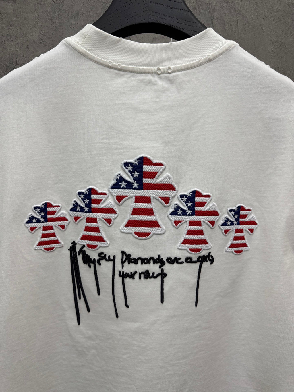 White T-shirt back with multiple embroidered patriotic figures and cursive text