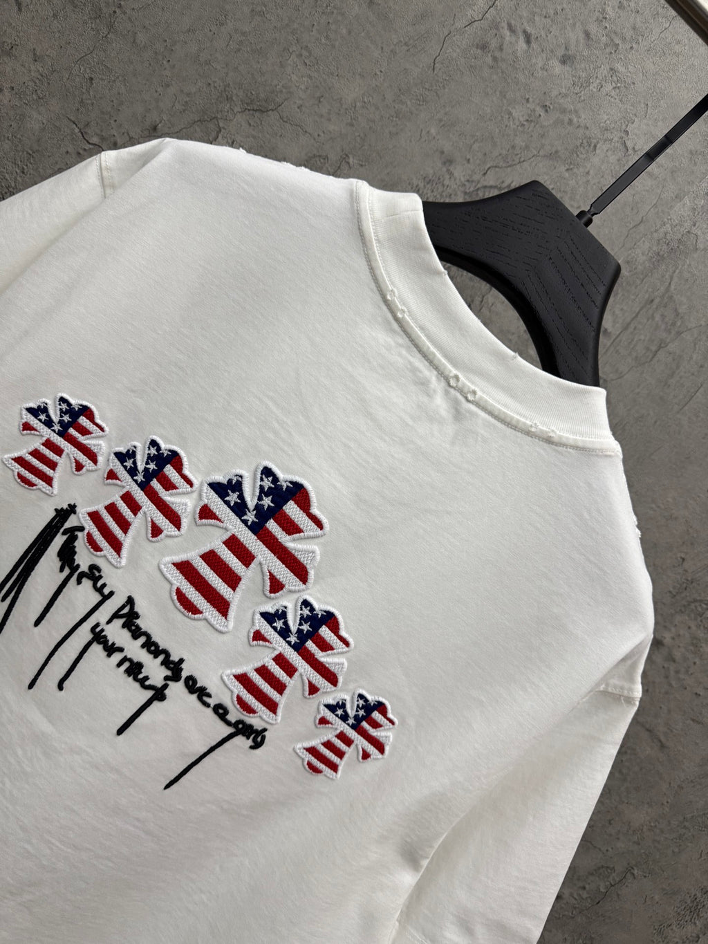 White T-shirt detail with multicolor patriotic drips and winged figure embroidery