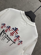 White T-shirt detail with multicolor patriotic drips and winged figure embroidery
