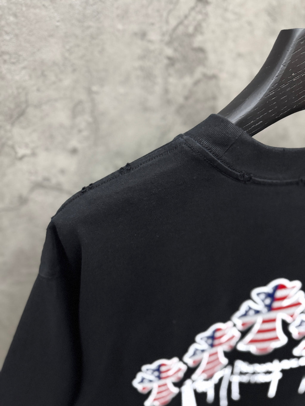 Side view of black T-shirt with partial USA angel graphic at the hem