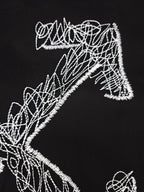 Black T-shirt close-up of white line-art graphic letterforms and shapes