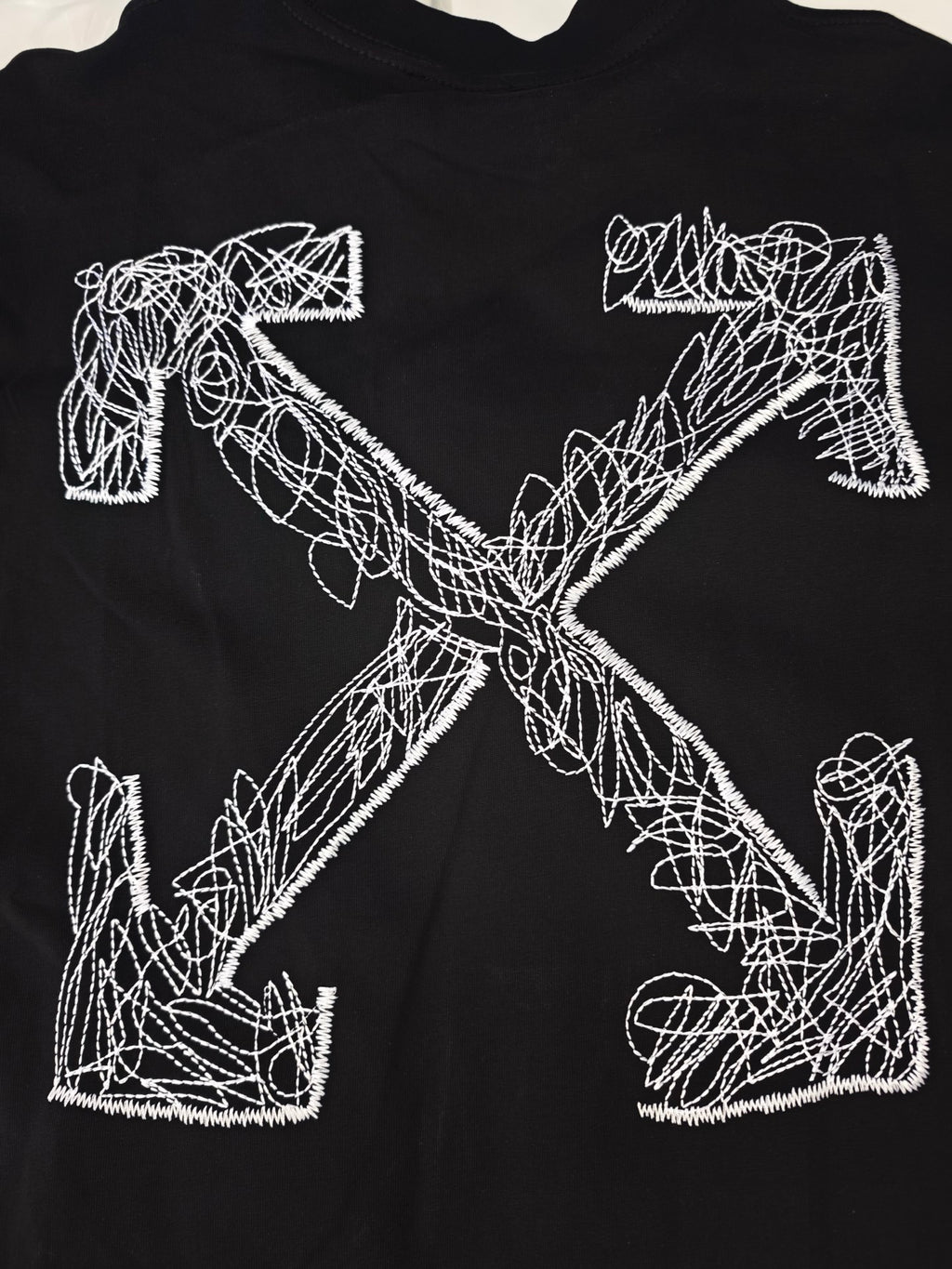 Black T-shirt with large white line-art cross graphic on the front