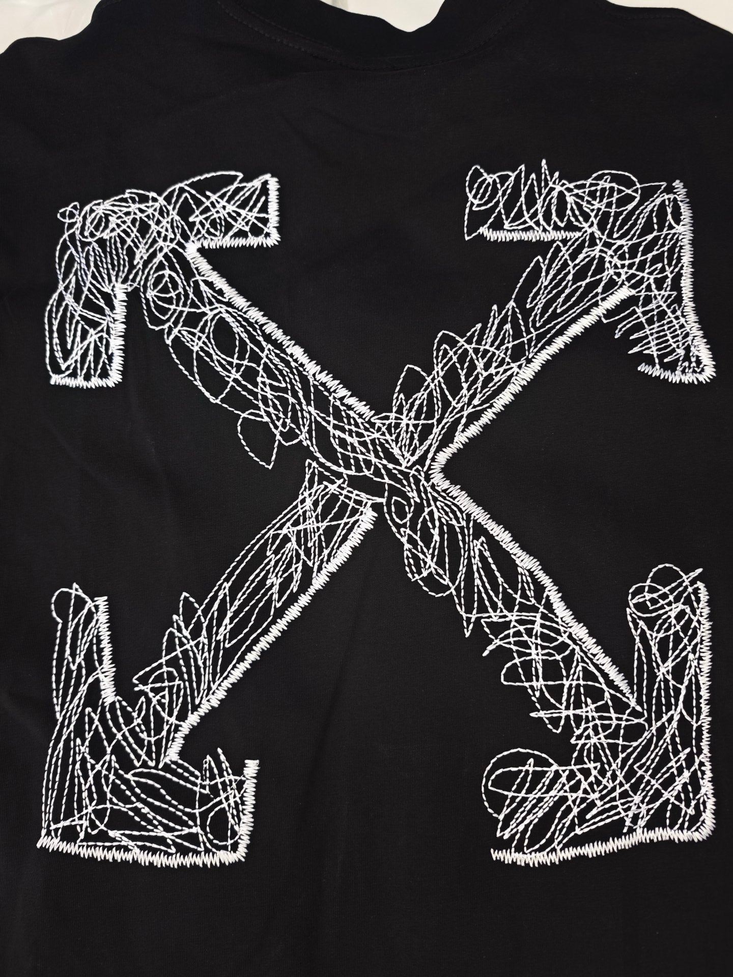 Black t-shirt with large white Off-White line-art graphic letters and cross design.