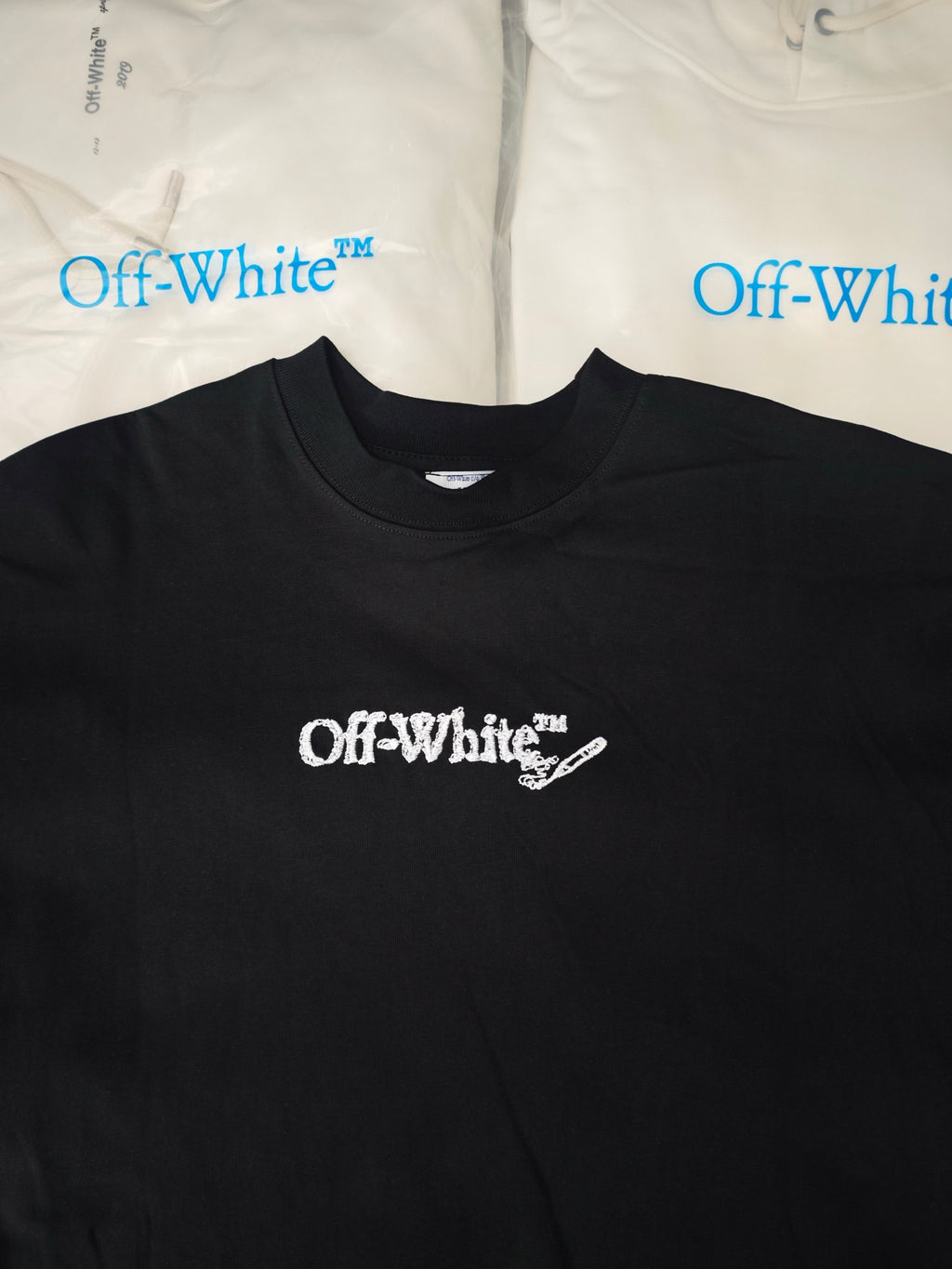 Black crewneck t-shirt with small white Off-White logo print at center chest.