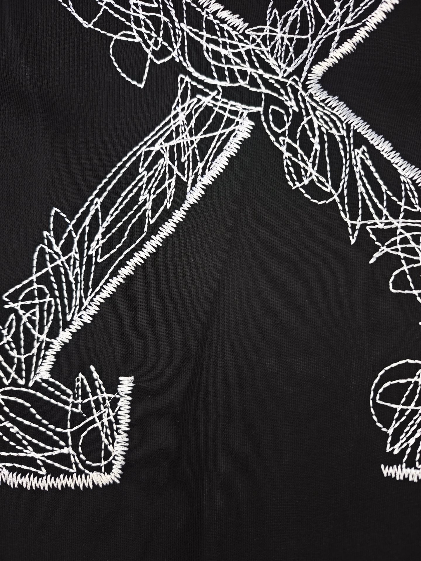 Black T-shirt close-up of white line-art graphic and stitched outlines