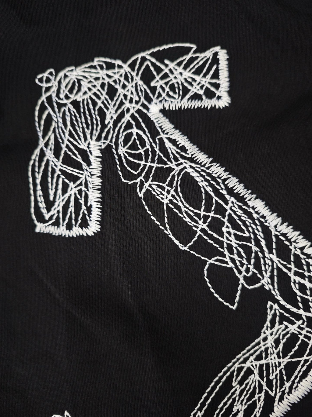 Black T-shirt close-up of white line-art graphic letterforms and outlines