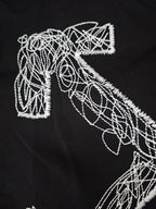 Black T-shirt close-up of white line-art graphic letterforms and outlines