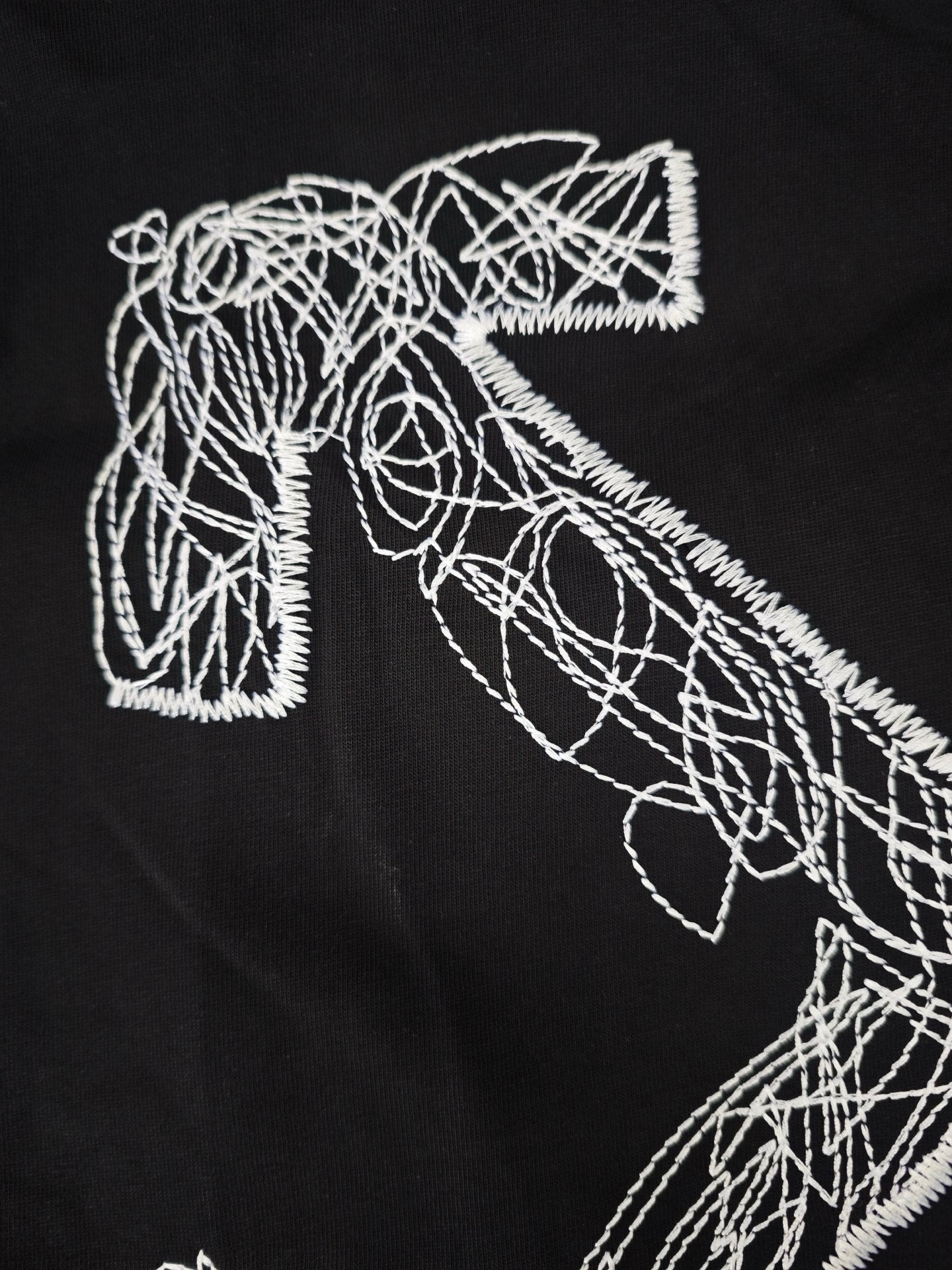 Close-up of white line-art graphic on a black t-shirt front.