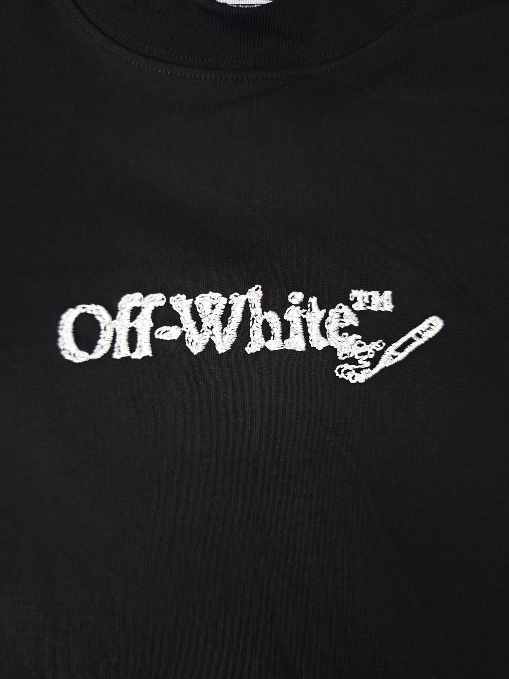 Close-up of white Off-White logo graphic on a black crewneck t-shirt.