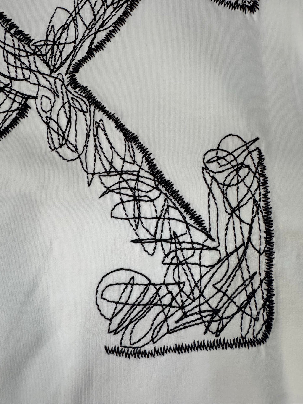 Off-White T-shirt front graphic close-up: black crossed arrow scribble
