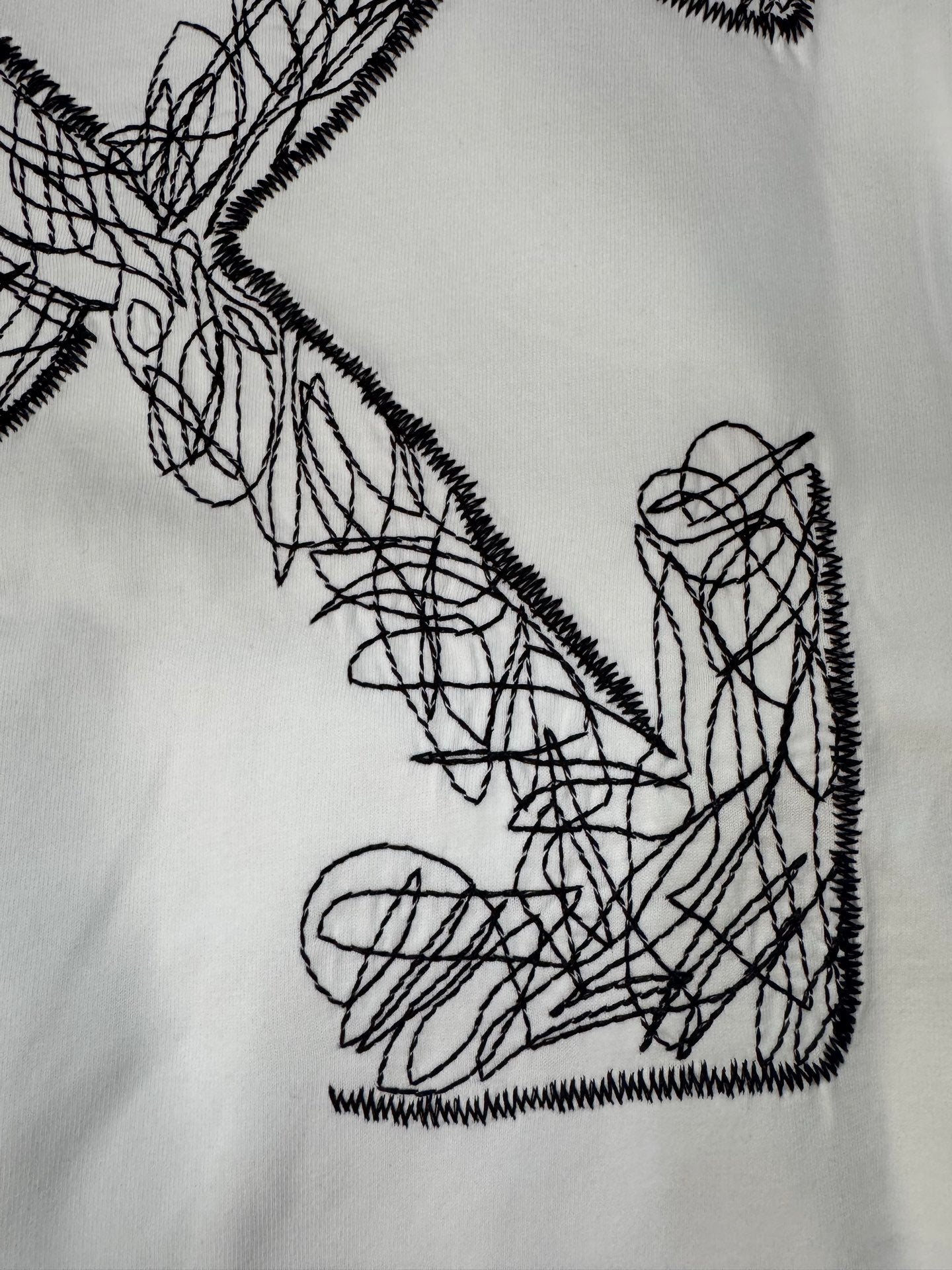 Off-White T-shirt front graphic close-up: black crossed arrow scribble