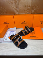 Black and tan slide sandals with two wide straps and open toe, side angle